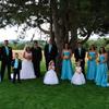 bridesmaids in teal blue dresses, flower girls in white dresses. Yellow and orange flowers. Men in black tuxedos with teal vests