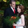 green fern with red and orange roses in bouquet. Bride tiara. Groom red tie